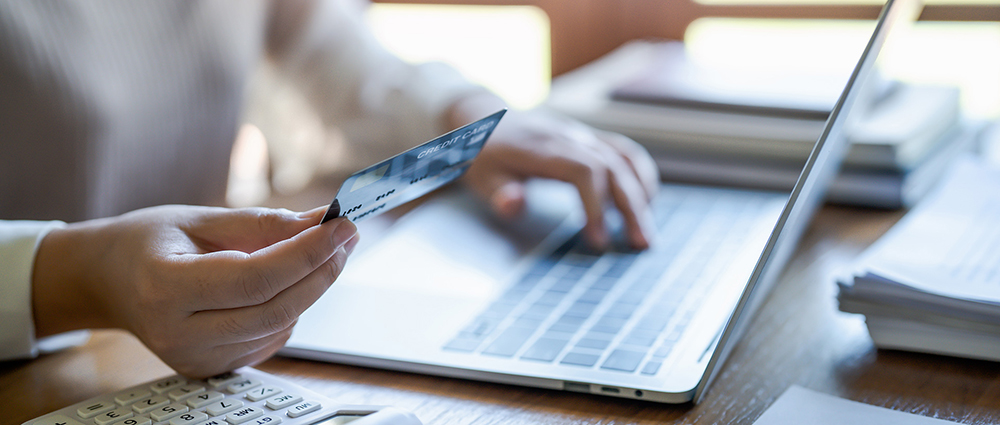 Woman holding a credit card by a laptop