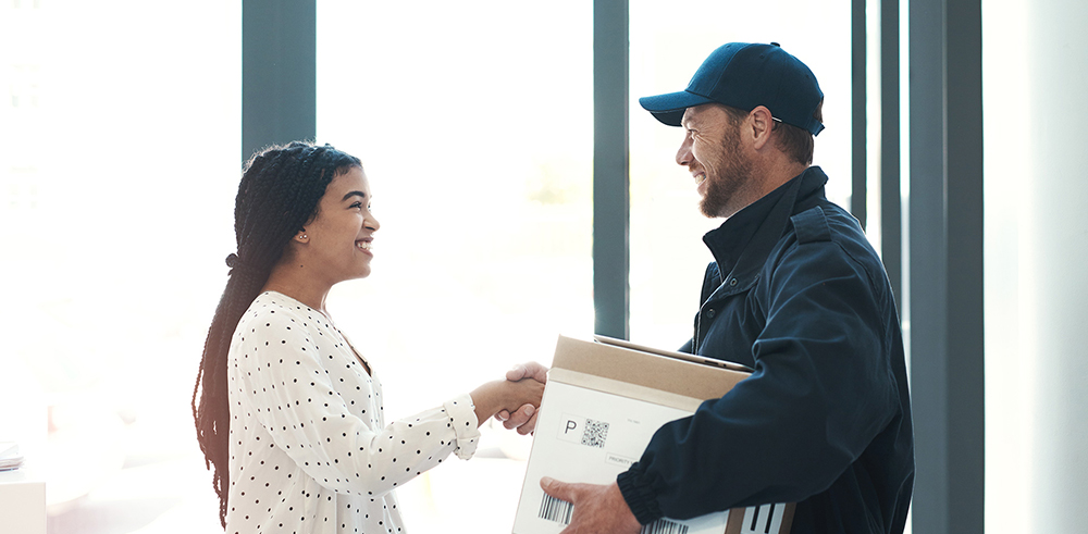 Delivery man dropping off package and shaking a woman's hand